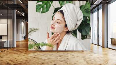 Young woman applying face mask at home. Natural Skin Care Routine. Cleaning face with natural cosmetics. Wall mural