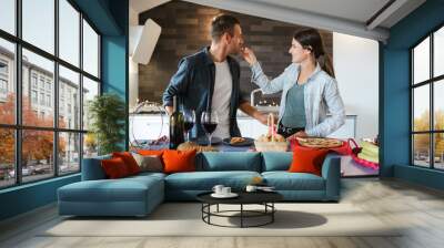 Couple of young millennials in love in the kitchen in the new apartment - Woman brings to the mouth with a piece of cake to the man Wall mural