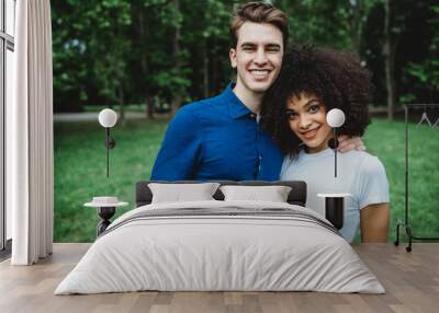 Portrait of millennials engaged couple at the park - A man and a woman hug each other Wall mural