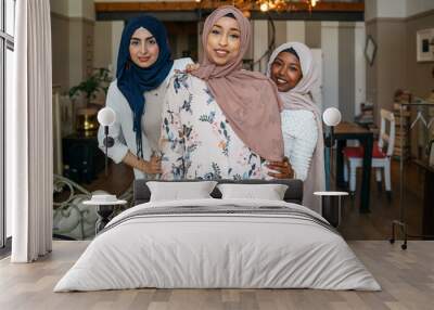 portrait of three muslim women with hijab at home - arab millennials embrace in an apartment Wall mural