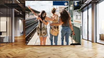 Three young beautiful female women at station to catch train for their vacation together during Coronavirus Covid-19 pandemic wearing protective face masks - Millennials have fun during the holidays Wall mural