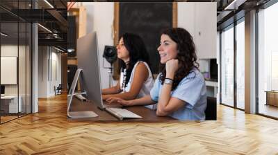 two young female friends work at the computer on a typical day at work in the office - millennials c Wall mural