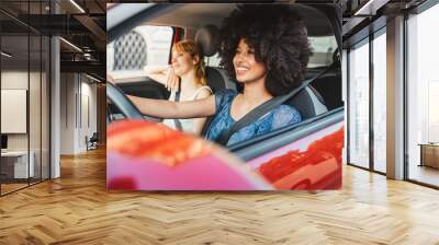 Two young women friends driving in the city - Millennials use the car to get around Wall mural