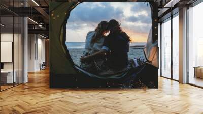 Young couple in love hug each other on the deserted beach on a summer evening at sunset during camping. Point of view inside the tent Wall mural