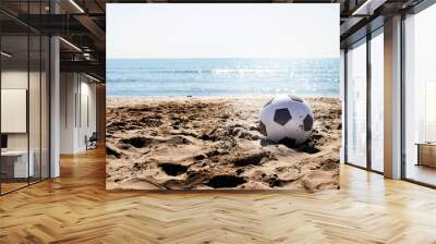 beach landscape with a soccer ball on the sand under a summer sun and in the background the water an Wall mural