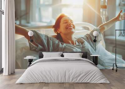 Caucasian cheerful woman patient with arms outstretched on hospital bed celebrating her recovery from surgery Wall mural