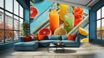 High angle view of a tray of fresh fruit juice in glass bottles and jugs on a blue wooden table with a summer background Wall mural