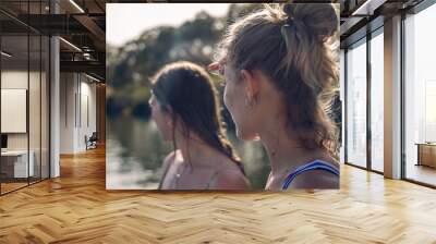 Back view headshot of two women, in costume, both looking towards the lake, illuminated by sunlight. Wall mural