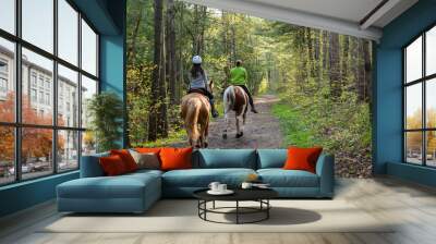 Two women horseback riding in the forest. Wall mural