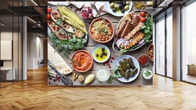 Middle eastern, arabic or mediterranean dinner table with grilled lamb kebab, chicken skewers  with roasted vegetables and appetizers variety serving on wooden outdoor table. Overhead view. Wall mural