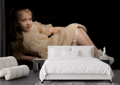 Cute little girl lying on the floor in the studio on a black bac Wall mural