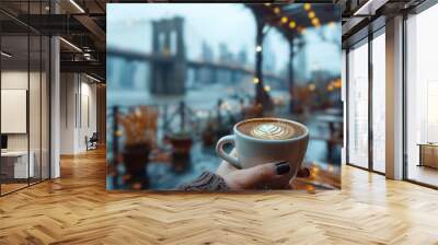 Close-up of a female hand holding a cup of coffee and Brooklyn Bridge is in the background, first-person photo, blurred background, travel image with well known destination Wall mural