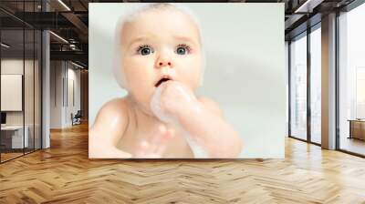 A Baby girl bathes in a bath with foam and soap bubbles Wall mural