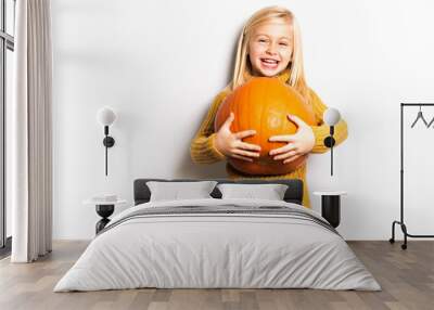 A Cute girl 5 year old posing in studio with pumpkin Wall mural