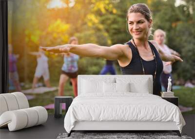 A group of adults attending a yoga class outside in park Wall mural