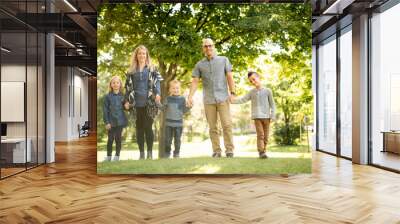 A Happy young family outside in green nature Wall mural