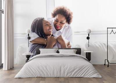 affectionate mother and daughter sitting on sofa Wall mural