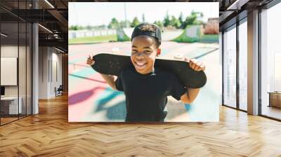 Afro-American boy with black t-shirt posing with his skateboard with the sky in the background Wall mural