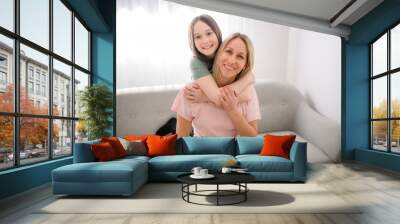 Beautiful pre teen girl with mother on the living room Wall mural