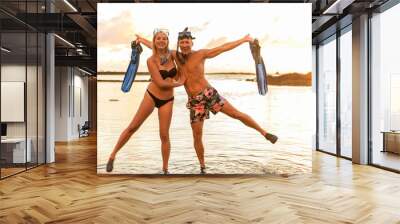 Couple is going to swim and snorkle on hawaii beach at the sunset Wall mural