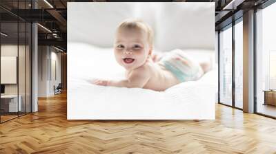 Cute happy 7 month baby girl in diaper lying and playing Wall mural