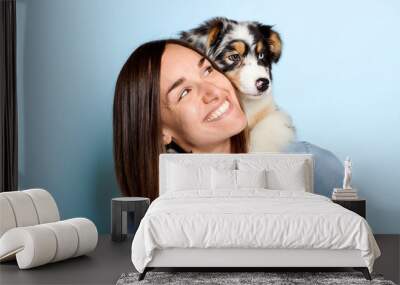 Handsome female with her Australian Berger puppy on studio blue Wall mural