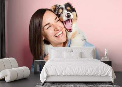 Handsome female with her Australian Berger puppy on studio pink Wall mural