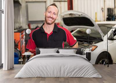 handsome mechanic based on car in auto repair shop with tablet on hand Wall mural