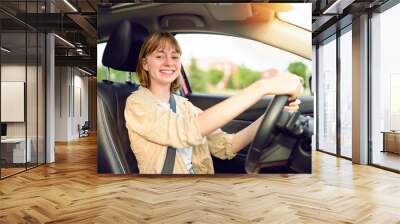 Happy teen girl driving a new car on sunset Wall mural