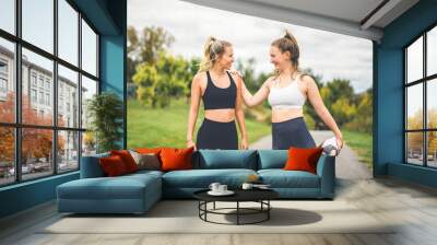 Healthy two sporty young girls jogging and stretching outdoors Wall mural