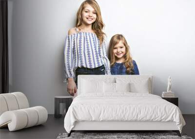 Joyful beautiful child with her sister close to a white wall Wall mural