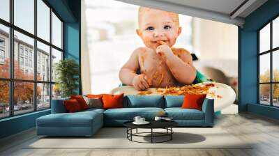 Little baby boy eating her dinner and making a mess Wall mural