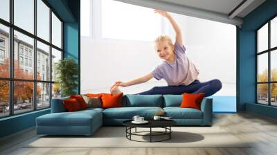 Little cute girl practicing yoga pose on a mat indoor Wall mural