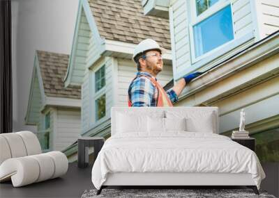 man with hard hat standing on steps inspecting house roof Wall mural