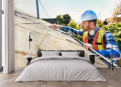 man with hard hat standing on steps inspecting house roof Wall mural