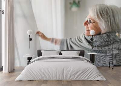 Middle aged female in front of curtains close to a window Wall mural