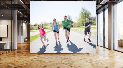 Parents with children sport running together outside Wall mural