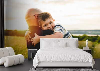 Portrait of a little boy with down syndrome in sunset on summer season with his father Wall mural