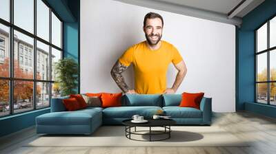 portrait of casual young man with beard and tattoo and Burnt Orange shirt on white background Wall mural