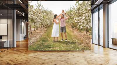 portrait of family and baby girl outdoors in apple tree flower Wall mural