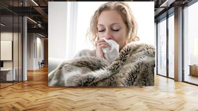 upset young woman sitting on sofa covered with blanket freezing blowing running nose got fever caught cold sneezing in tissue, sick girl having influenza symptoms coughing at home, flu concept Wall mural