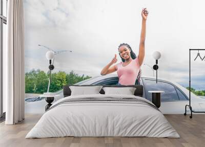 Young black teenage driver seated in her new car Wall mural