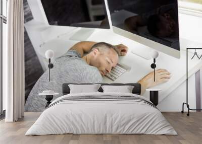 Young man With computer Sleeping At Desk In Office Wall mural