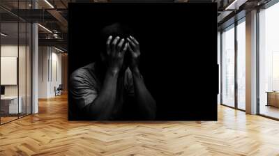 Man sitting alone felling sad worry or fear and hands up on head on black background Wall mural