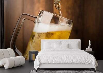 Pouring cool beer from bottle into glass on wood wall backgroud alcohol celebration concept Wall mural