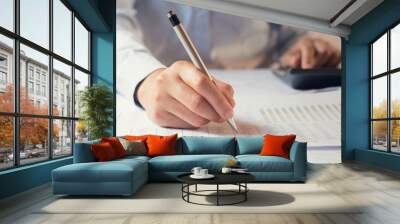 .accountant working on desk to using calculator with penaccountant working on desk to using calculator with pen Wall mural