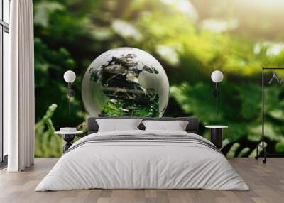 crystal globe glass resting on stone with green leaf and sunshine in nature forset. eco  environment concept Wall mural