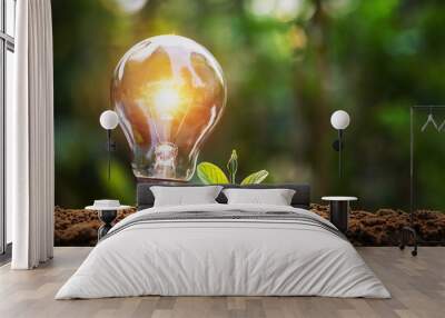 lightbulb with small plant on soil and sunshine. concept saving energy in nature Wall mural