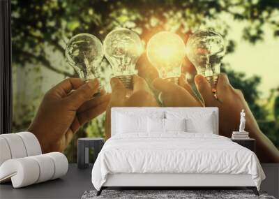 solar energy concept hand group holding light bulb in nature Wall mural