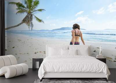 young woman stretching before the workout on tropical beach, seychelles, digue island Wall mural